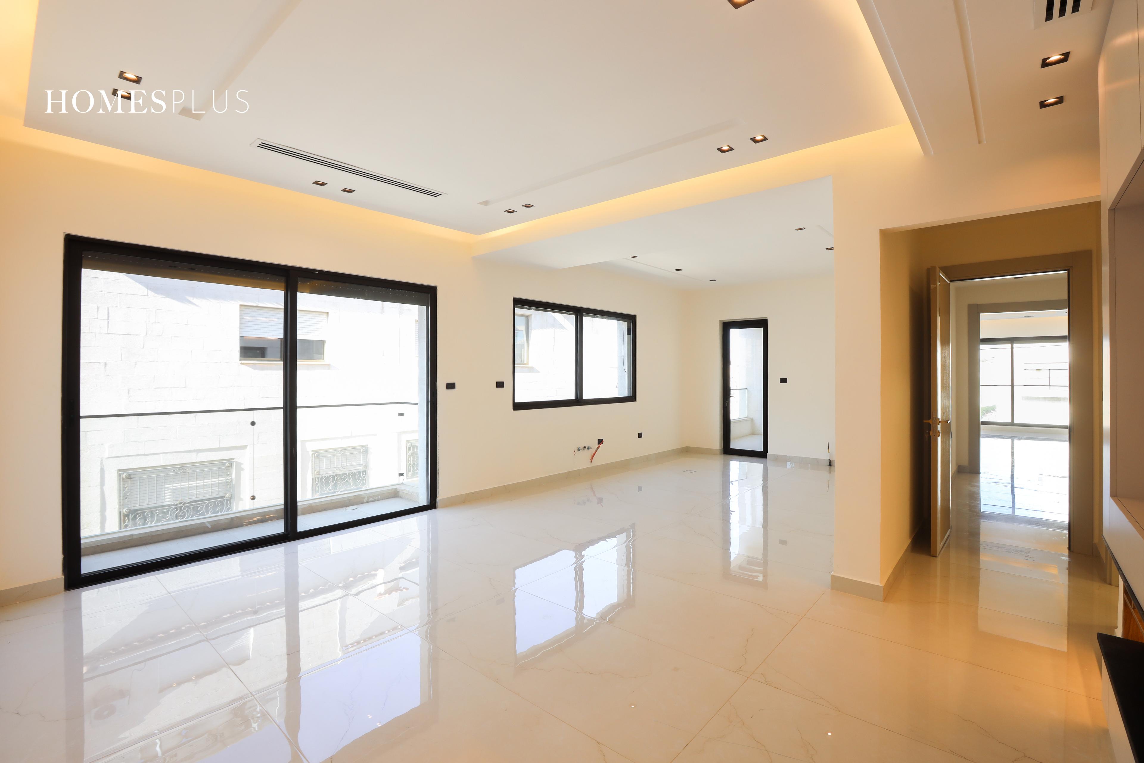 Bright empty living room with large windows in an apartment in Abdoun, Amman
