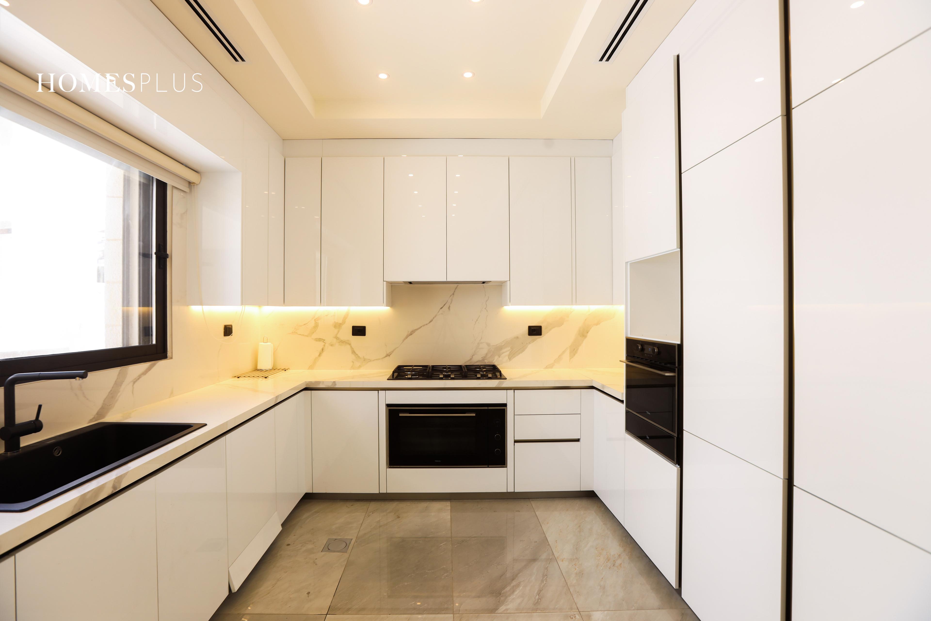 White fitted kitchen in an apartment in Abdoun, Amman