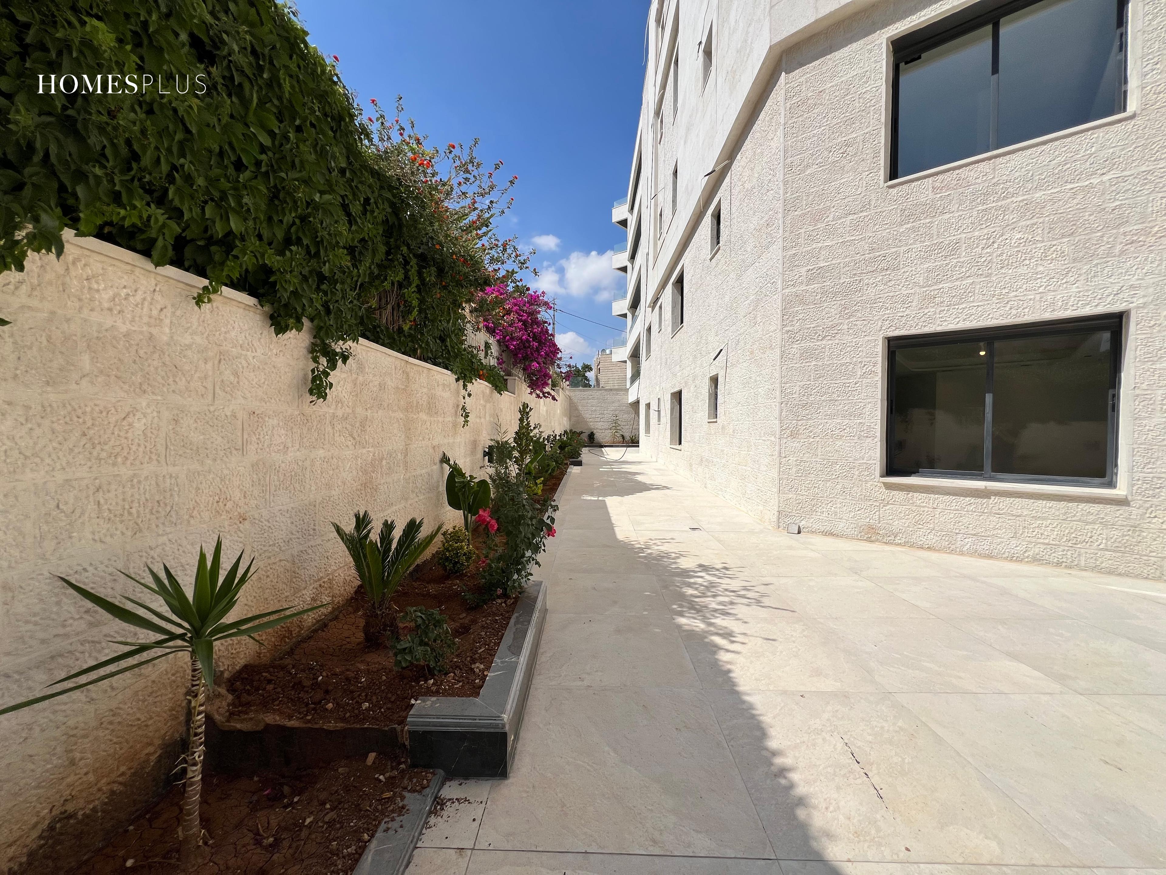 Paved side garden with plants beside an apartment building in Jabal Amman