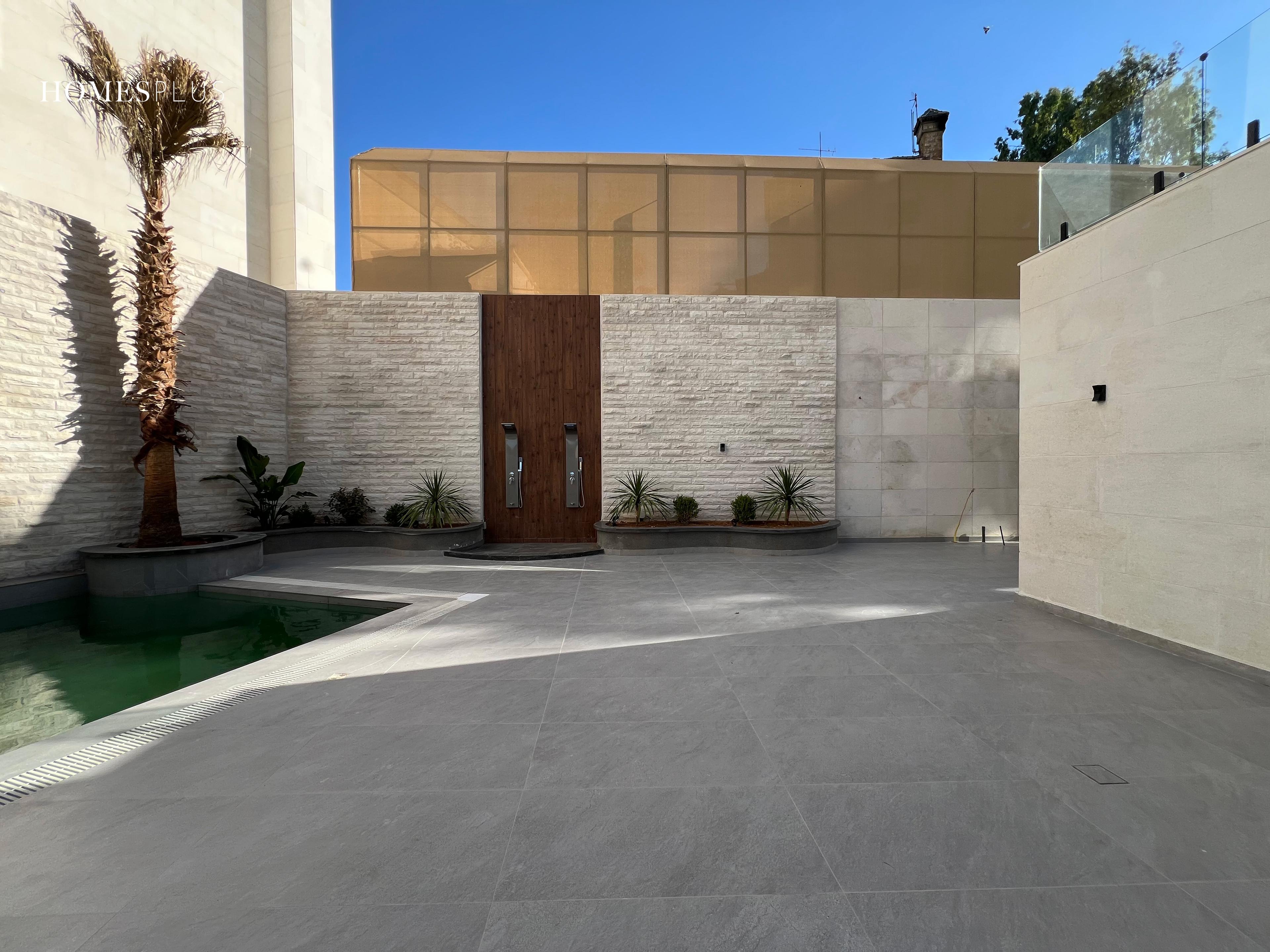 Paved courtyard with a stone wall and a wooden gate, Jabal Amman