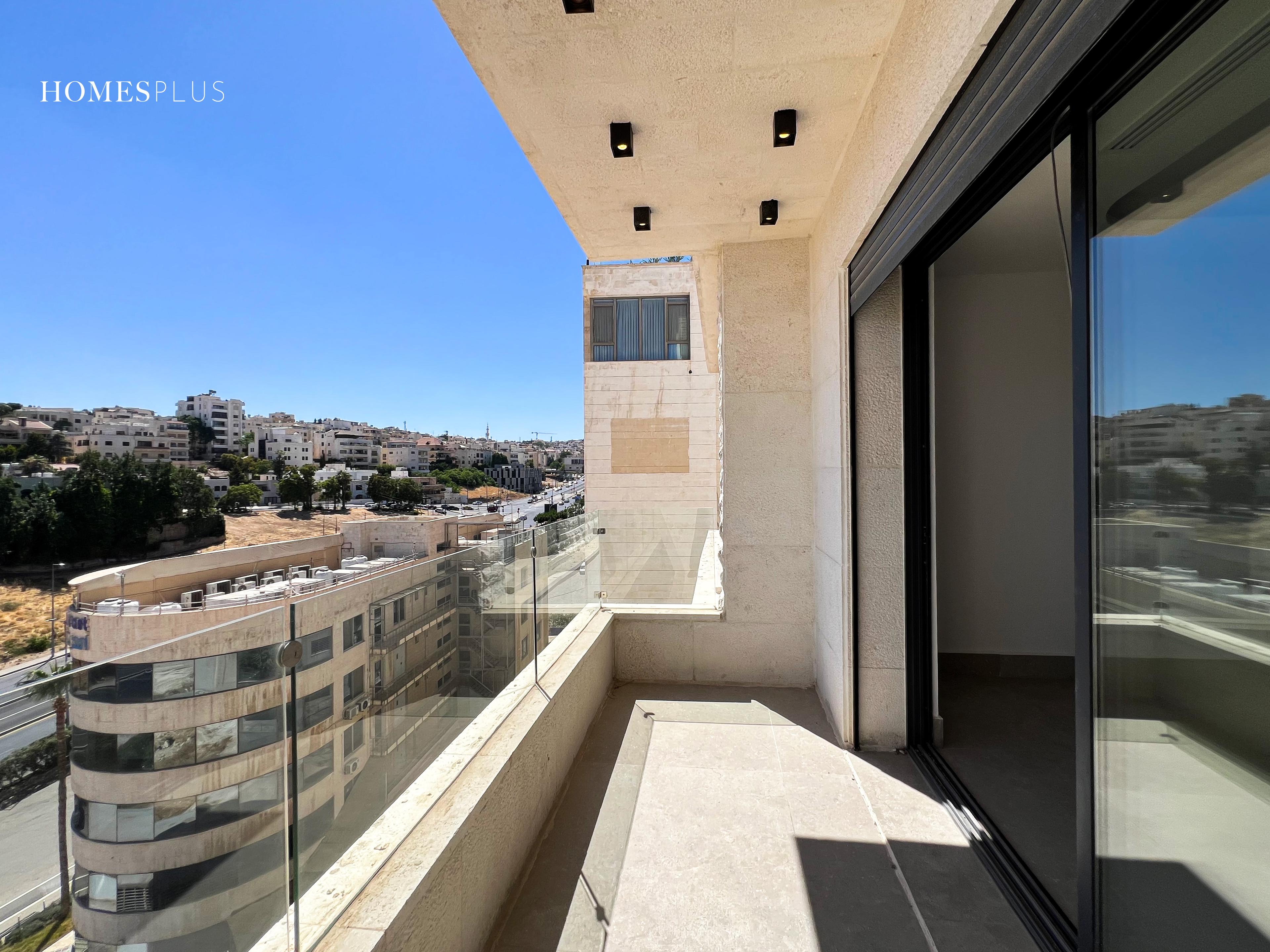 Balcony with a glass railing and a view over the hills, Jabal Amman
