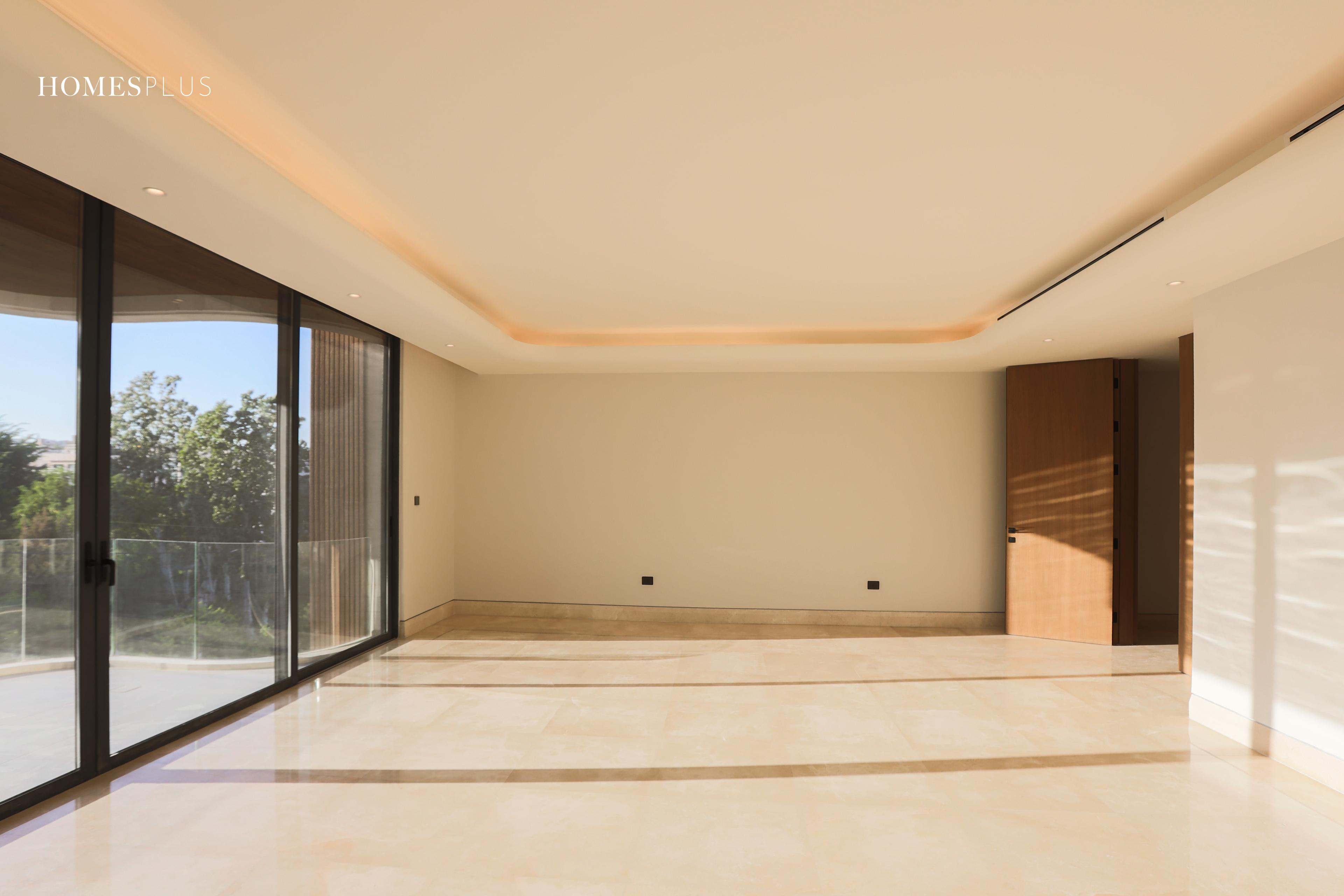 Empty living room with warm ceiling lighting and wide windows, Jabal Amman